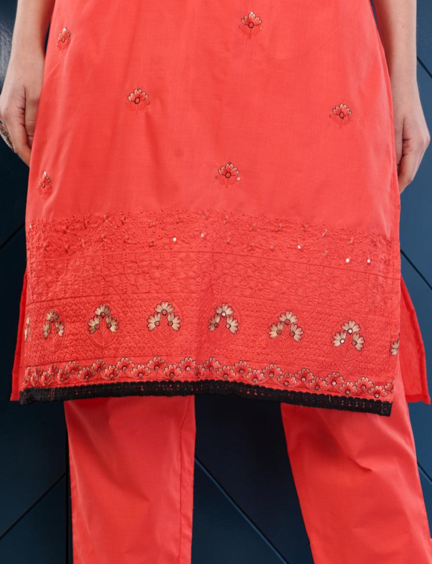 Eelika coral red cotton salwar suit with intricate floral embroidery and a black lace border on the knee-length top
