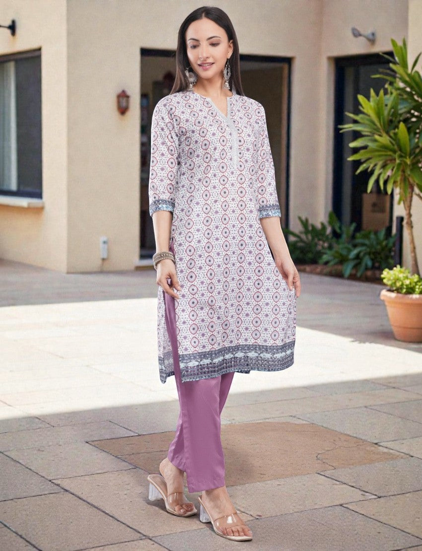 Model wearing an Eelika cotton printed calf-length kurta with V-neck, 3/4 sleeves, and matching purple trousers.