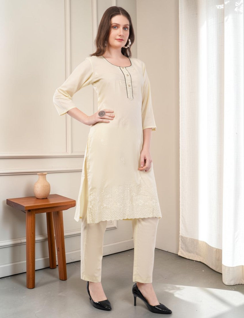 Model wearing an Eelika cream cotton salwar suit with 3/4 sleeves, round neck, and delicate embroidered hem details.