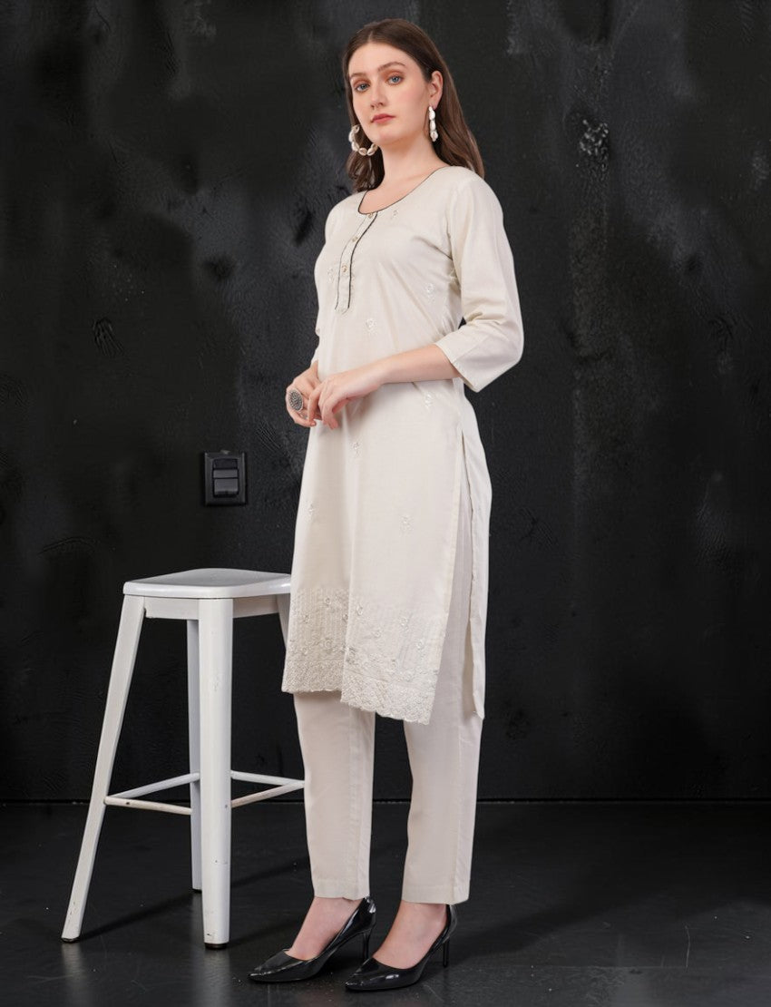 Model wearing an off-white Eelika cotton salwar suit set with 3/4 sleeves, knee-length tunic, and matching trousers.