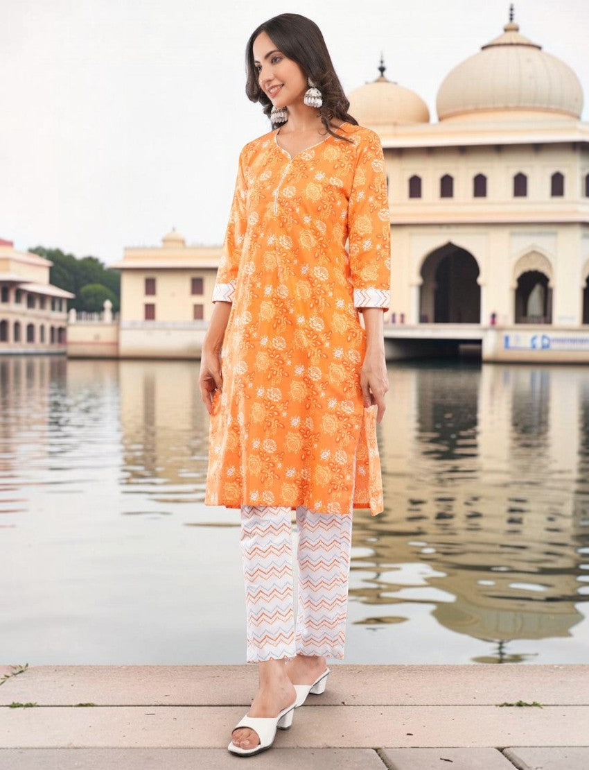 Eelika orange cotton salwar suit set with floral paisley print, V-neck, 3/4 sleeves, and patterned trousers.
