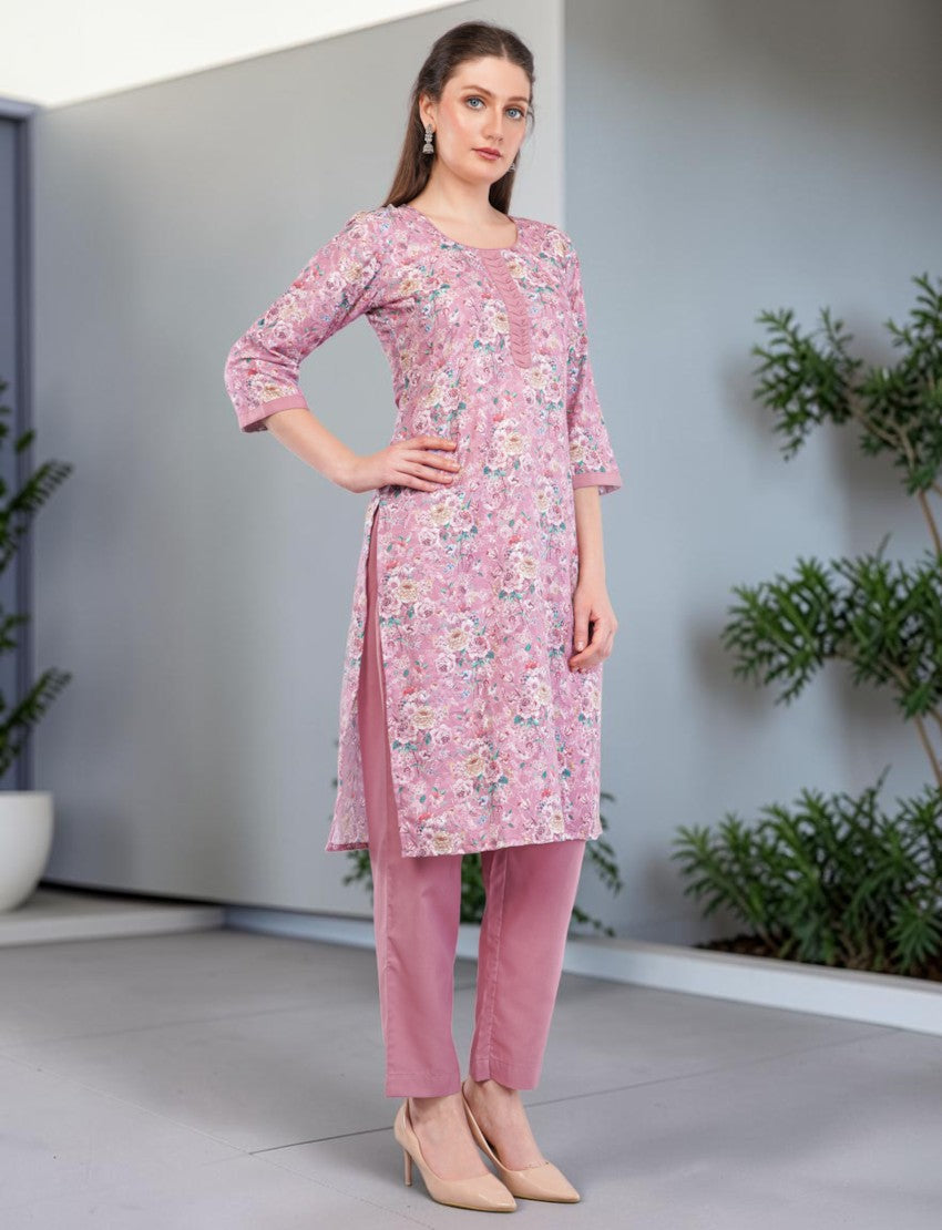 Model wearing an Eelika pink floral print cotton salwar suit with 3/4th sleeves, calf-length kurta, and trousers.