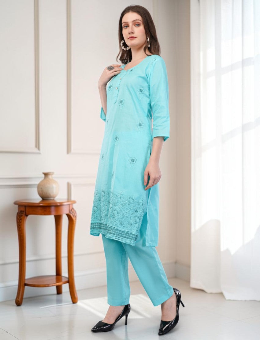 Model wearing an Eelika turquoise cotton salwar suit with 3/4 sleeves, intricate embroidery, and matching trousers.