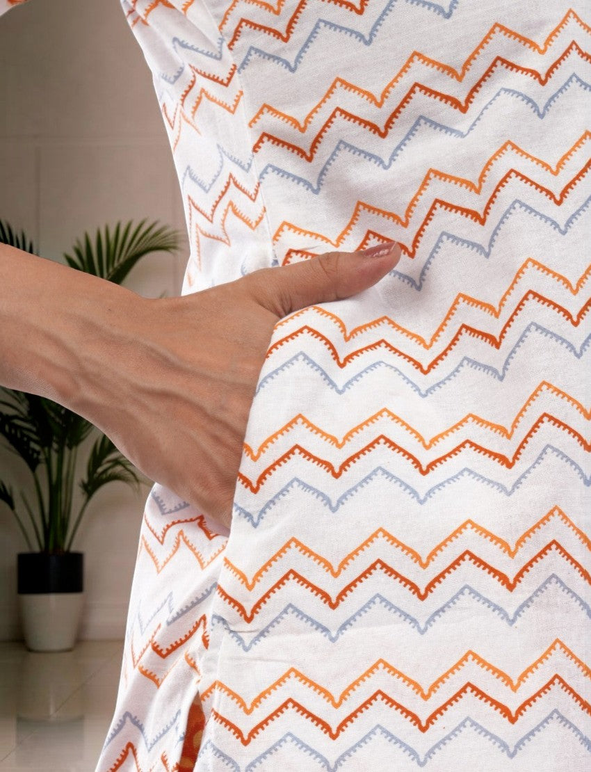 Eelika white cotton salwar suit featuring a geometric orange and blue zigzag print with a functional side pocket