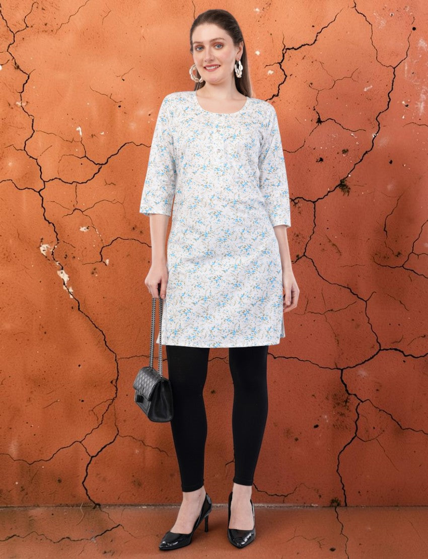 Eelika women's white cotton kurti with blue floral print, round neck, and 3/4 sleeves, worn with black leggings.