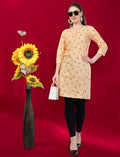 Eelika women's yellow cotton kurti with floral print, round neck, and 3/4 sleeves, styled with black leggings.